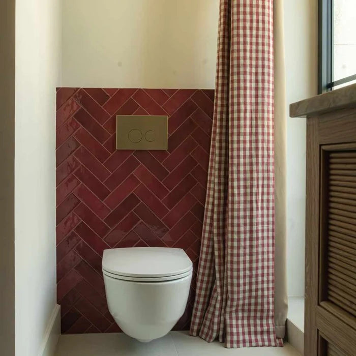 Carrelage Artisan Burgundy effet zellige brillant posé en chevrons dans des toilettes